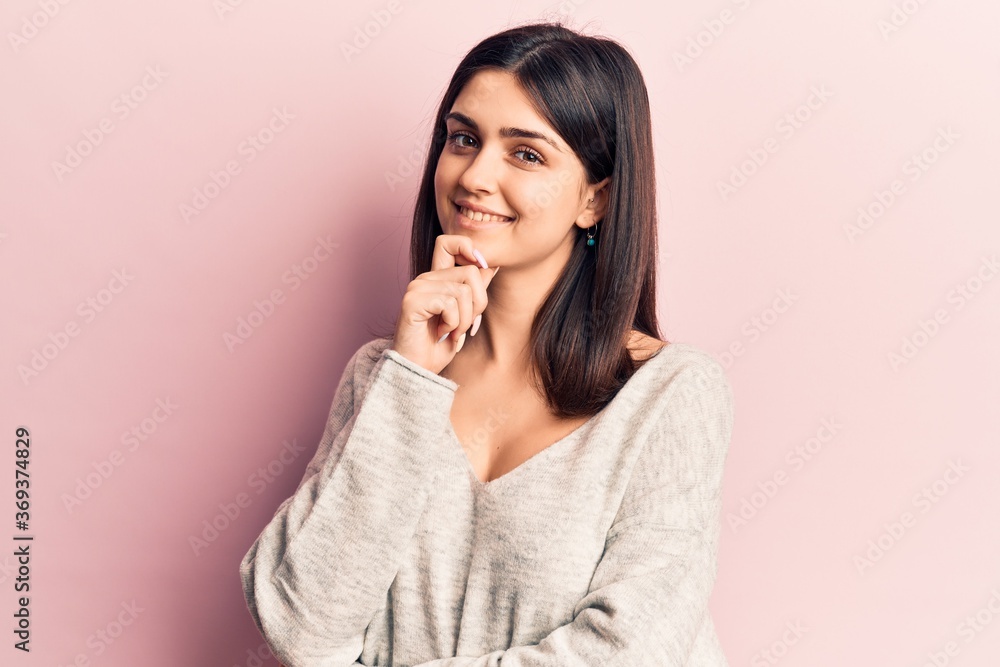 Young beautiful girl wearing casual sweater smiling looking confident at the camera with crossed arms and hand on chin. thinking positive. Young beautiful girl wearing casual sweater smiling looking confident at the camera with crossed arms and hand on chin. thinking positive.