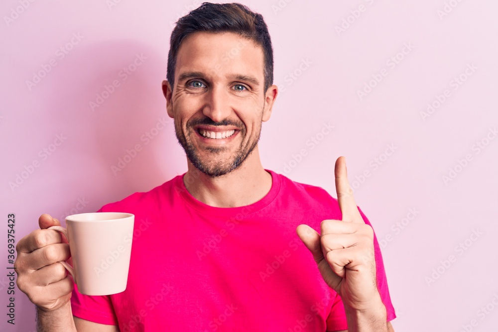 Young handsome man drinking cup off coffee standing over isolated pink background smiling with an idea or question pointing finger with happy face, number one Young handsome man drinking cup off coffee standing over isolated pink background smiling with an idea or question pointing finger with happy face, number one
