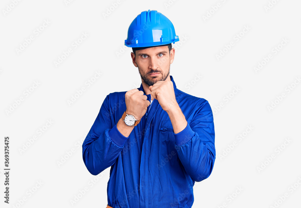 Young handsome man wearing worker uniform and hardhat looking sleepy and tired, exhausted for fatigue and hangover, lazy eyes in the morning.