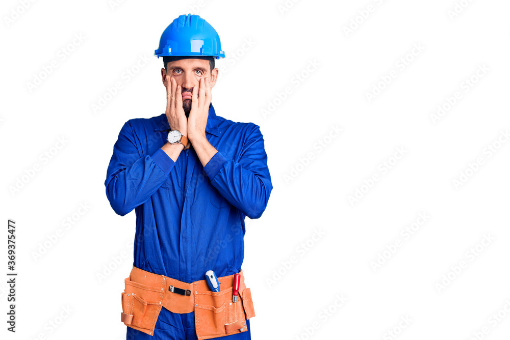 Young handsome man wearing worker uniform and hardhat worried and stressed about a problem with hand on forehead, nervous and anxious for crisis