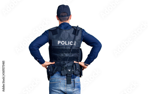 Young handsome man wearing police uniform standing backwards looking away with arms on body