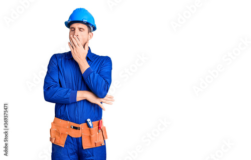 Young handsome man wearing worker uniform and hardhat bored yawning tired covering mouth with hand. restless and sleepiness. © Krakenimages.com
