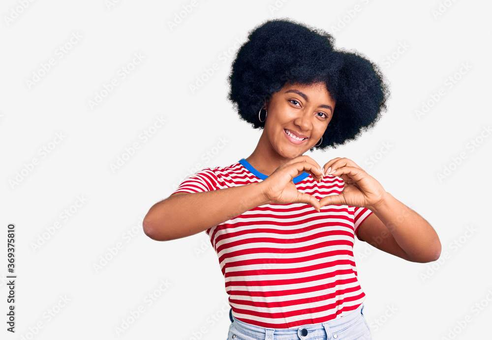 Young african american girl wearing casual clothes smiling in love showing heart symbol and shape with hands. romantic concept. Young african american girl wearing casual clothes smiling in love showing heart symbol and shape with hands. romantic concept.