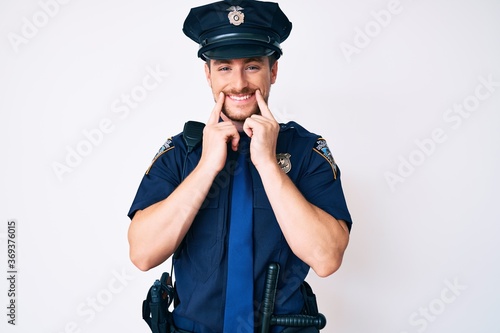 Young caucasian man wearing police uniform smiling with open mouth, fingers pointing and forcing cheerful smile