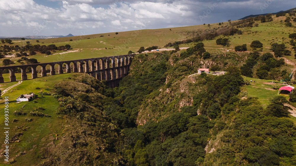 Aerial photograph of a natural landscape in Tepotzotlan, Estado de Mexico, Mexico, where the mountains, a cloudy sky, trees and arches of the site can be seen 2.