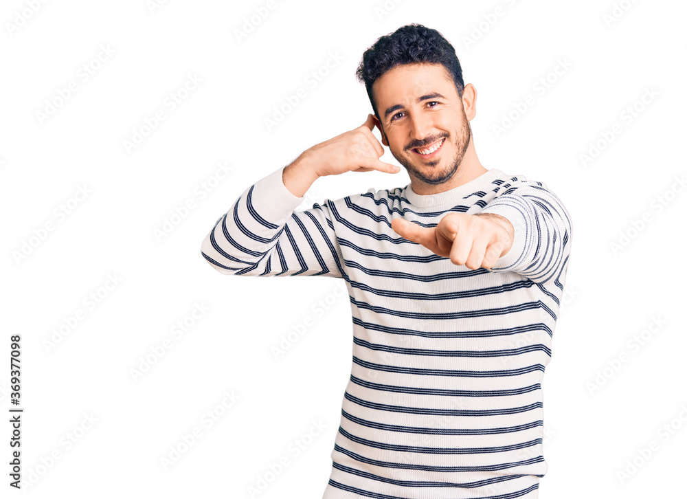 Fototapeta premium Young hispanic man wearing casual clothes smiling doing talking on the telephone gesture and pointing to you. call me.
