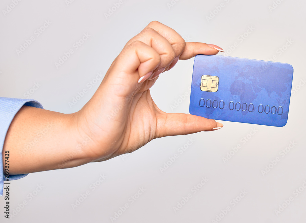 Hand of caucasian young woman holding credit card over isolated white background Hand of caucasian young woman holding credit card over isolated white background