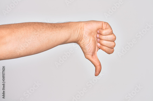 Hand of caucasian young man showing fingers over isolated white background doing thumbs down rejection gesture, disapproval dislike and negative sign