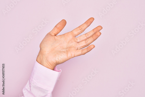 Hand of caucasian young man showing fingers over isolated pink background presenting with open palm  reaching for support and help  assistance gesture