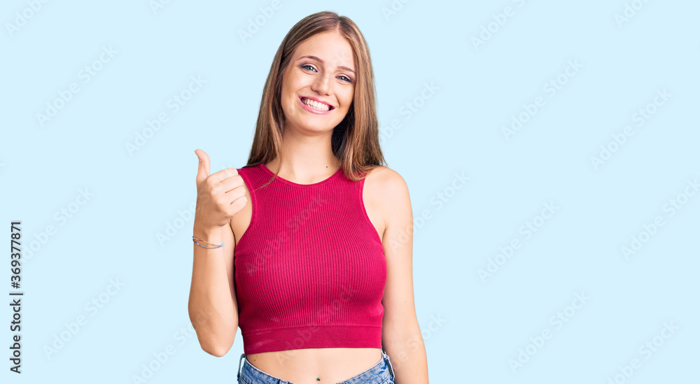 Young beautiful blonde woman wearing elegant summer shirt doing happy thumbs up gesture with hand. approving expression looking at the camera showing success. Young beautiful blonde woman wearing elegant summer shirt doing happy thumbs up gesture with hand. approving expression looking at the camera showing success.