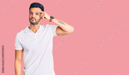 Young handsome hispanic man wearing casual clothes pointing unhappy to pimple on forehead, ugly infection of blackhead. acne and skin problem © Krakenimages.com