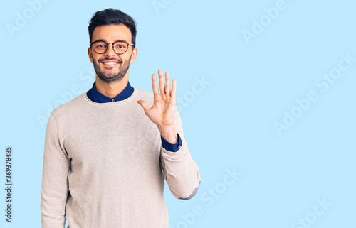 Young handsome hispanic man wearing elegant clothes and glasses showing and pointing up with fingers number five while smiling confident and happy. © Krakenimages.com
