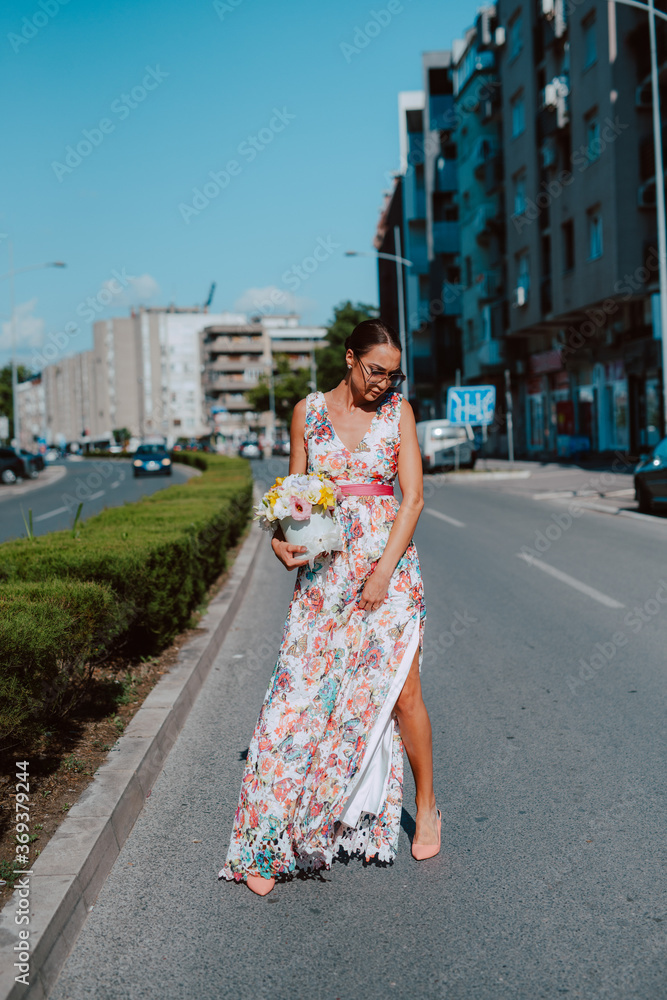 Young beautiful stylish caucasian woman model in summer dress with flower box in her hand on the street Young beautiful stylish caucasian woman model in summer dress with flower box in her hand on the street