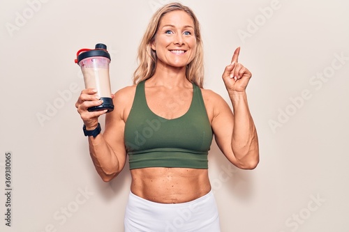 Middle age caucasian blonde woman wearing sport clothes drinking a protein shake surprised with an idea or question pointing finger with happy face, number one © Krakenimages.com
