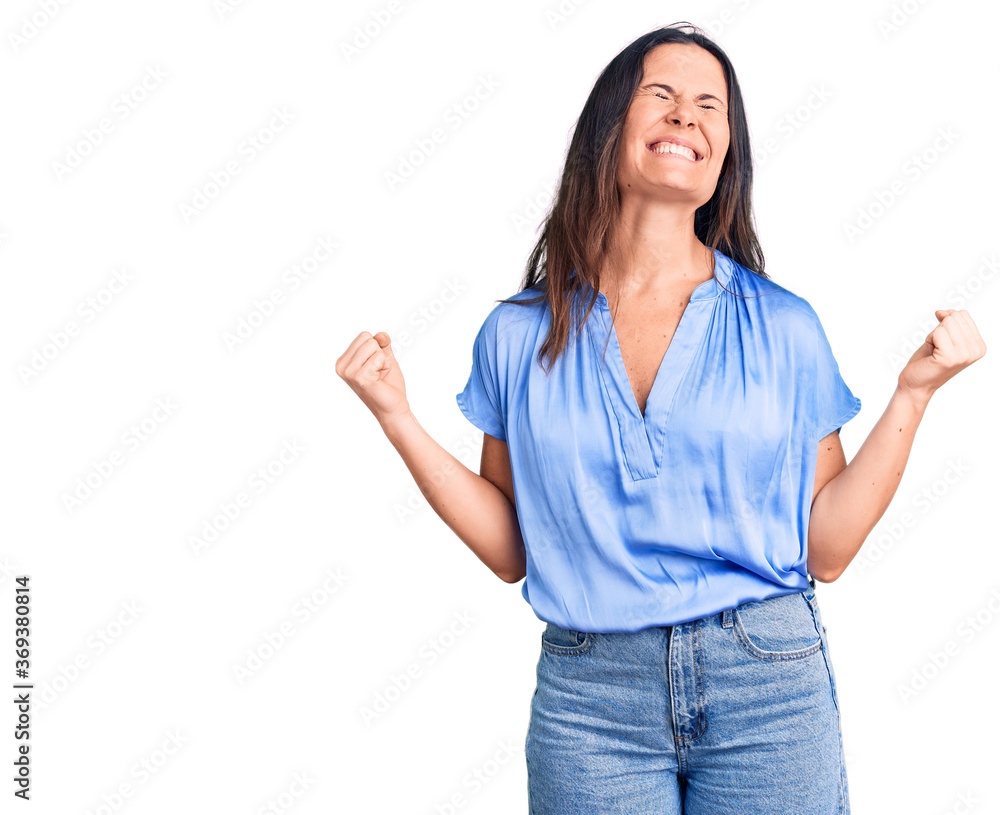 Young beautiful brunette woman wearing casual t-shirt very happy and excited doing winner gesture with arms raised, smiling and screaming for success. celebration concept. Young beautiful brunette woman wearing casual t-shirt very happy and excited doing winner gesture with arms raised, smiling and screaming for success. celebration concept.