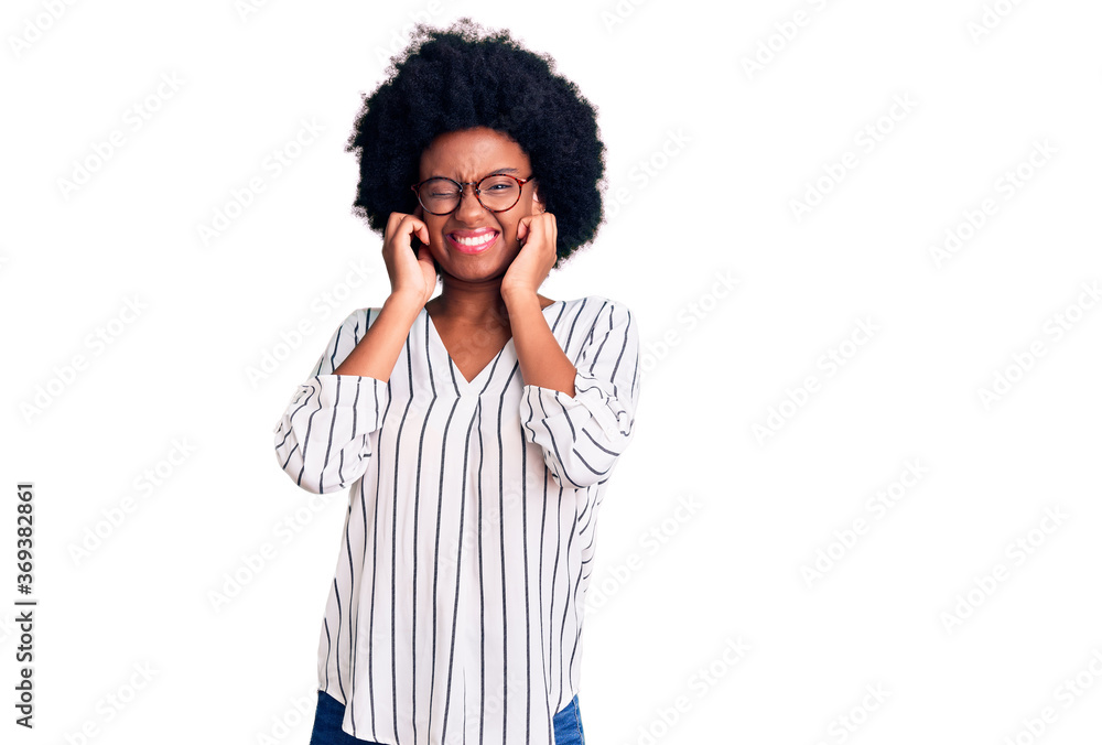 Young african american woman wearing casual clothes and glasses covering ears with fingers with annoyed expression for the noise of loud music. deaf concept. Young african american woman wearing casual clothes and glasses covering ears with fingers with annoyed expression for the noise of loud music. deaf concept.
