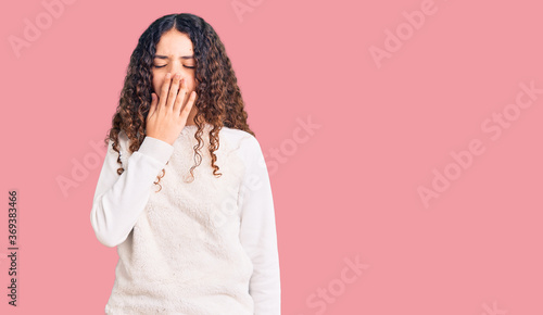 Beautiful kid girl with curly hair wearing casual clothes bored yawning tired covering mouth with hand. restless and sleepiness. © Krakenimages.com