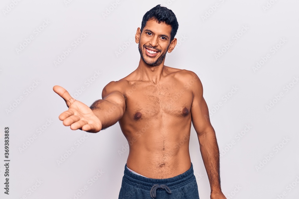 Young latin man standing shirtless smiling friendly offering handshake as greeting and welcoming. successful business. Young latin man standing shirtless smiling friendly offering handshake as greeting and welcoming. successful business.