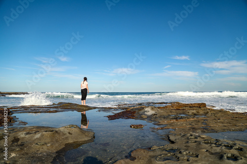 Pre-teen girl exploring rock pools on Newcastle Beach in NSW  Australia 