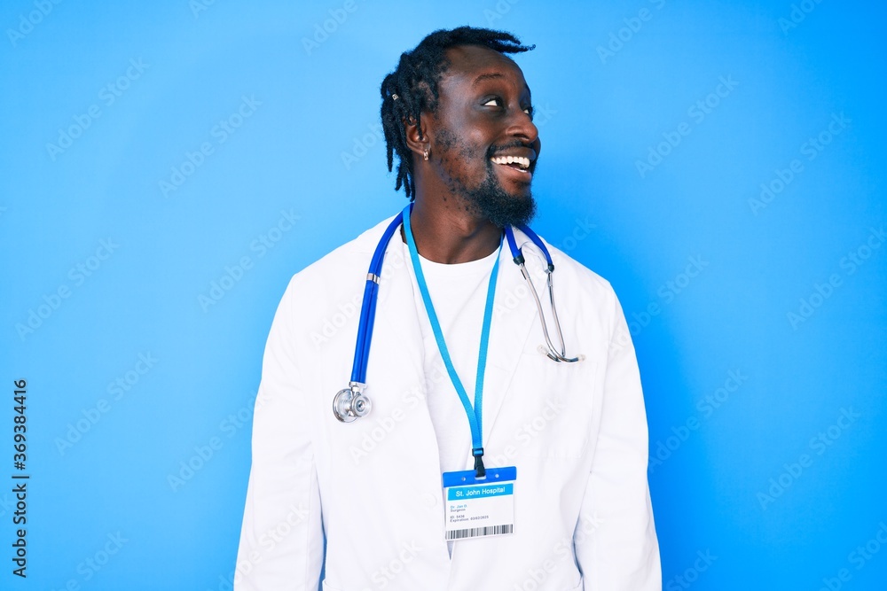 Young african american man with braids wearing doctor stethoscope and id pass looking away to side with smile on face, natural expression. laughing confident. Young african american man with braids wearing doctor stethoscope and id pass looking away to side with smile on face, natural expression. laughing confident.