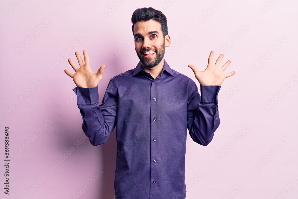 Young handsome man with beard wearing casual shirt showing and pointing up with fingers number ten while smiling confident and happy. Young handsome man with beard wearing casual shirt showing and pointing up with fingers number ten while smiling confident and happy.
