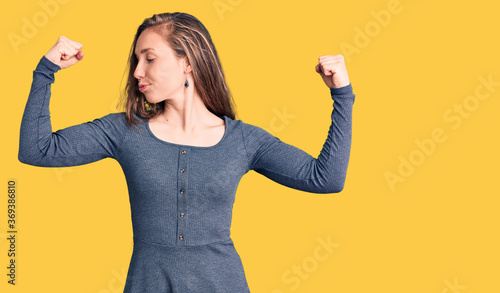 Young beautiful blonde woman wearing casual dress showing arms muscles smiling proud. fitness concept.