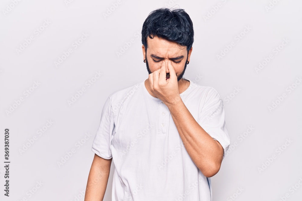 Young hispanic man wearing casual clothes tired rubbing nose and eyes feeling fatigue and headache. stress and frustration concept. Young hispanic man wearing casual clothes tired rubbing nose and eyes feeling fatigue and headache. stress and frustration concept.
