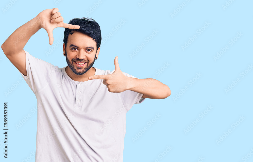 Young hispanic man wearing casual clothes smiling making frame with hands and fingers with happy face. creativity and photography concept. Young hispanic man wearing casual clothes smiling making frame with hands and fingers with happy face. creativity and photography concept.