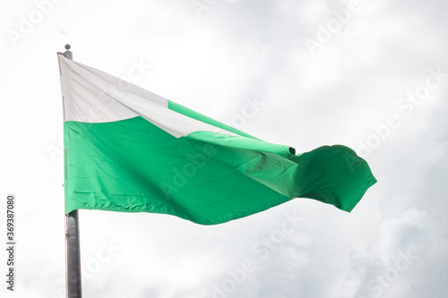 Flag of Antioquia waving in a blue cloudy sky