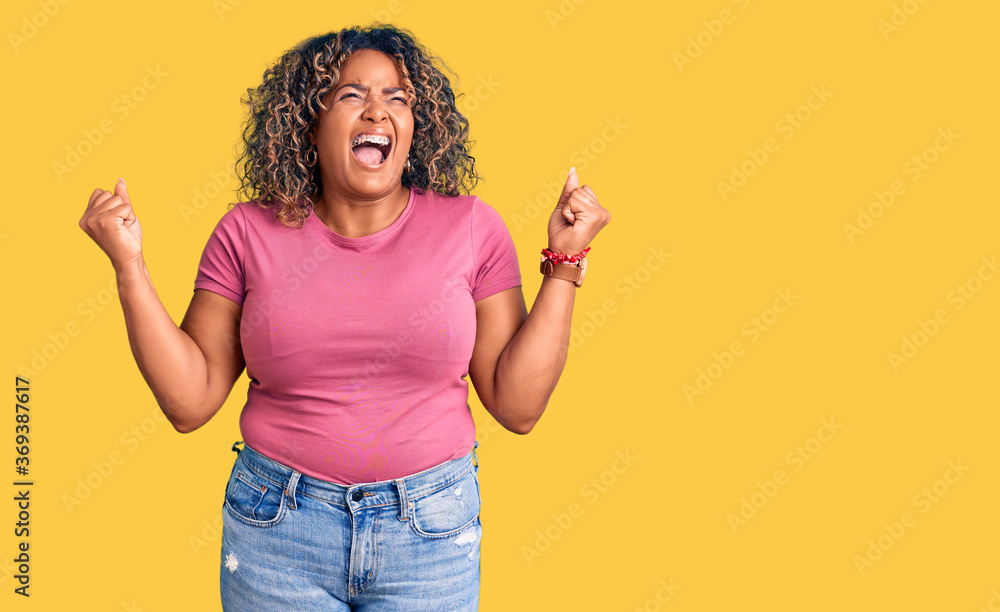 Young african american plus size woman wearing casual clothes crazy and mad shouting and yelling with aggressive expression and arms raised. frustration concept. Young african american plus size woman wearing casual clothes crazy and mad shouting and yelling with aggressive expression and arms raised. frustration concept.