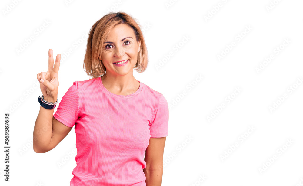 Young blonde woman wearing sportswear smiling looking to the camera showing fingers doing victory sign. number two. Young blonde woman wearing sportswear smiling looking to the camera showing fingers doing victory sign. number two.