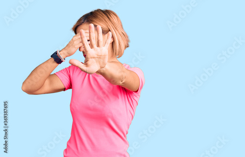 Young blonde woman wearing sportswear covering eyes with hands and doing stop gesture with sad and fear expression. embarrassed and negative concept.