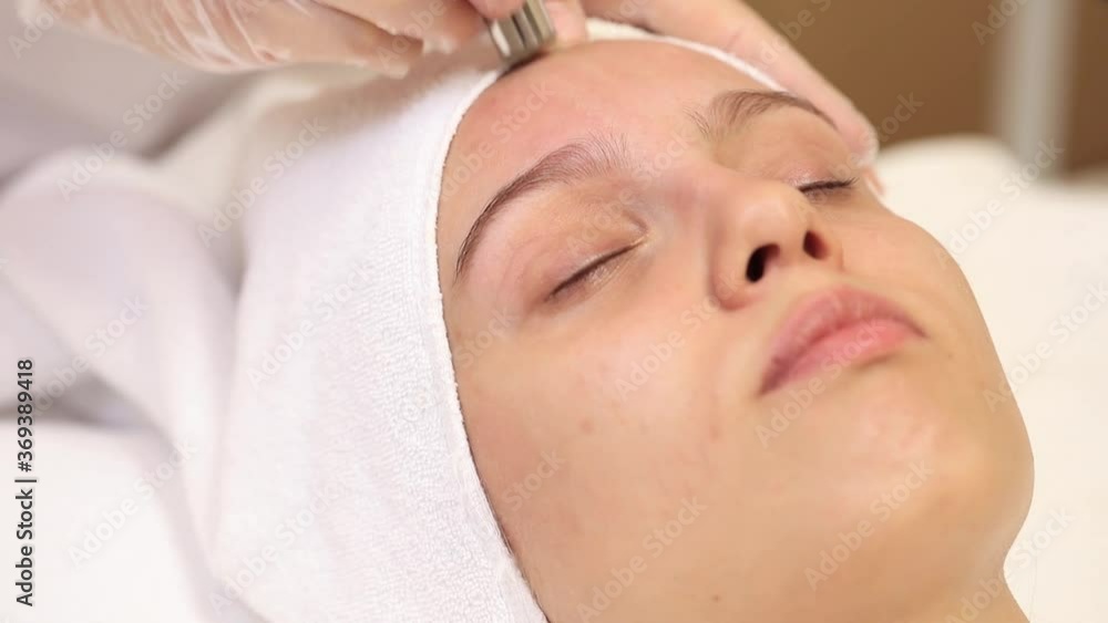 A young and beautiful woman is given a diamond facial cleansing. A young and beautiful woman is given a diamond facial cleansing.