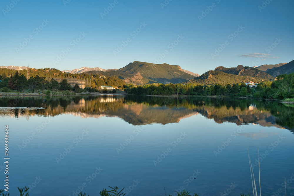 Reflection on estes lake shows peaceful sunrise morning scene. Calm water gives reflection of the surrounding landscape