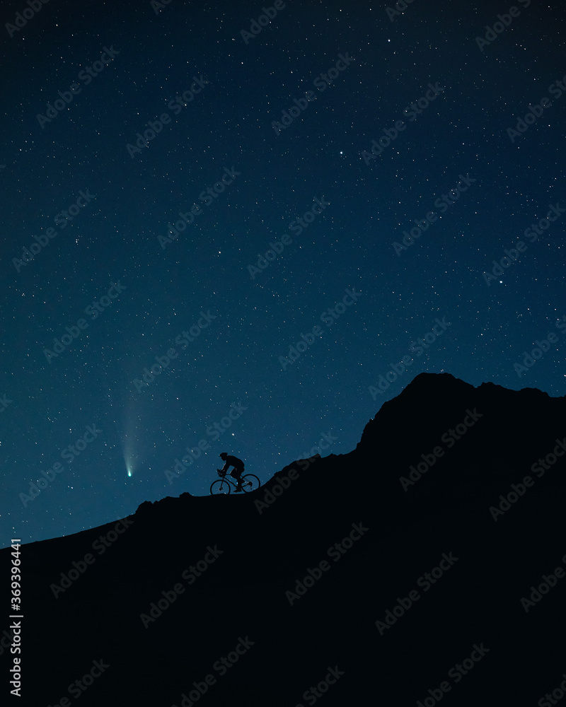Comet Neowise and man riding the bicycle at night