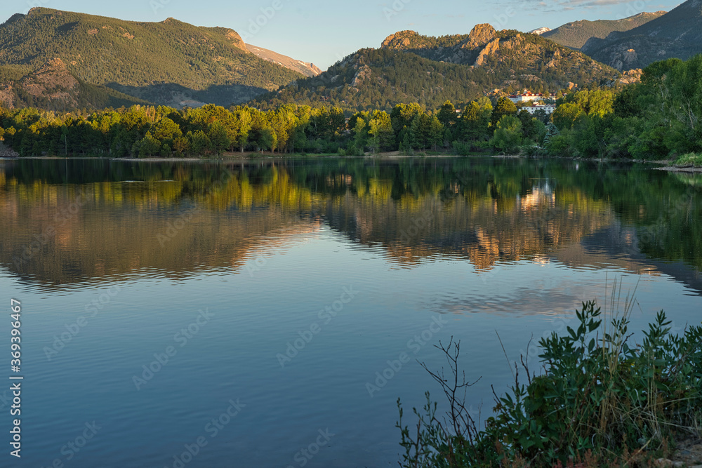 Reflection on estes lake shows peaceful sunrise morning scene. Calm water gives reflection of the surrounding landscape