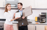 Young man and woman choosing material for kitchen furniture in salon