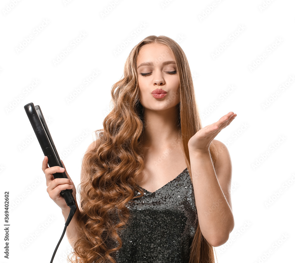 Beautiful young woman with flattening iron for hair against white background Beautiful young woman with flattening iron for hair against white background