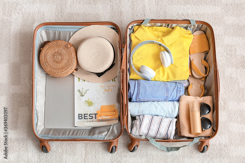 Packed suitcase with belongings on floor. Travel concept photo
