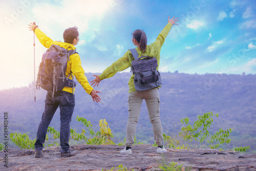 Couples hiker standing and open arms on mountain peak celebrate their freedom vacation 