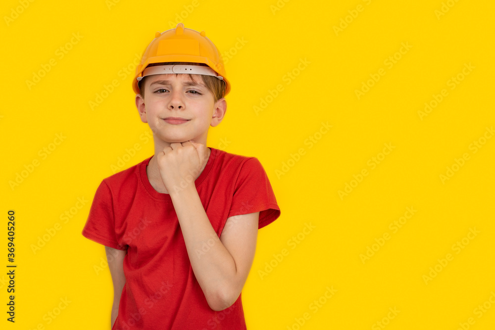 Teen boy in hard hat on yellow background. Choice of profession. Copy space