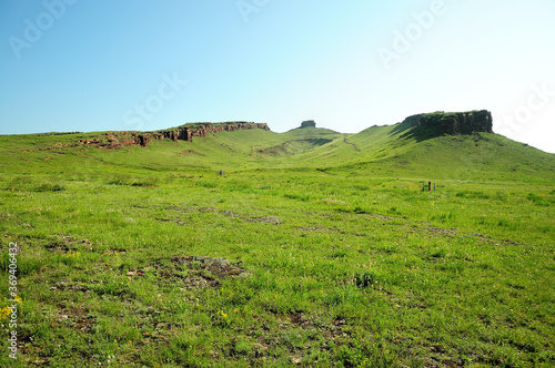 A deep intermountain hollow overgrown with grass and a stone peak of an unusual shape. photo