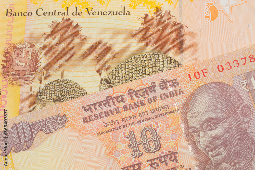 A macro image of a orange ten rupee bill from India paired up with a colorful, yellow five Bolivar bank note from Venezuela.  Shot close up in macro.