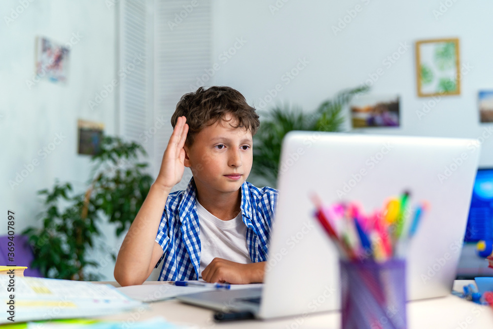 focused schoolboy with headphones uses a laptop for distance learning focused schoolboy with headphones uses a laptop for distance learning