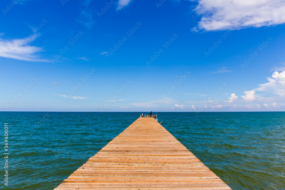Wooden bridge extending into the sea with Deep Blue ocean sky clouds. Landscape with Ocean small waves water reflection copy space for text. Illustration for tourism, website or ad. Andaman sea.