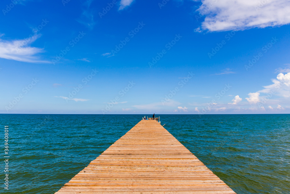 Wooden bridge extending into the sea with Deep Blue ocean sky clouds. Landscape with Ocean small waves water reflection copy space for text. Illustration for tourism, website or ad. Andaman sea. Wooden bridge extending into the sea with Deep Blue ocean sky clouds. Landscape with Ocean small waves water reflection copy space for text. Illustration for tourism, website or ad. Andaman sea.