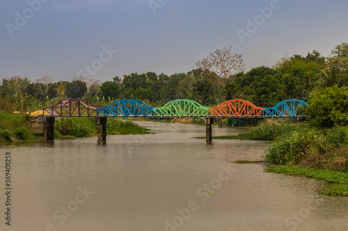 A contemporary coloured metal rainbow bridge over a canal. Arch bridge. Selective focus.