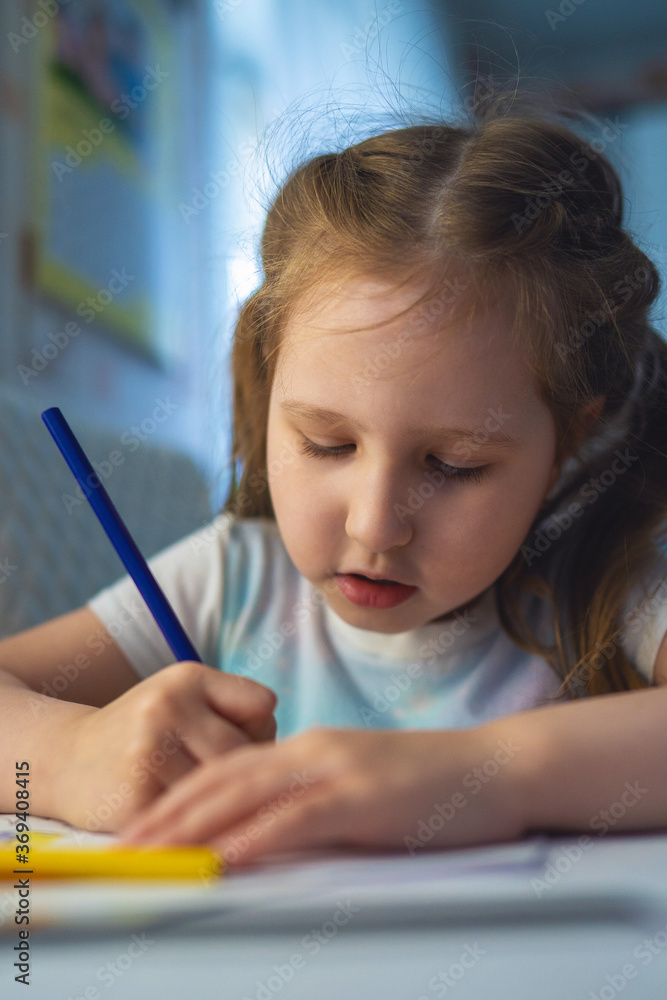 cute little girl draws a picture with colored pencils. the child draws at the table cute little girl draws a picture with colored pencils. the child draws at the table