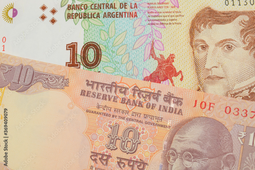 A macro image of a orange ten rupee bill from India paired up with a colorful ten peso note from Argentina.  Shot close up in macro.