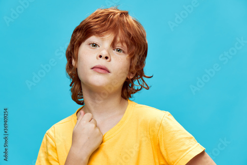 Red-haired child in a yellow T-shirt on a blue background 